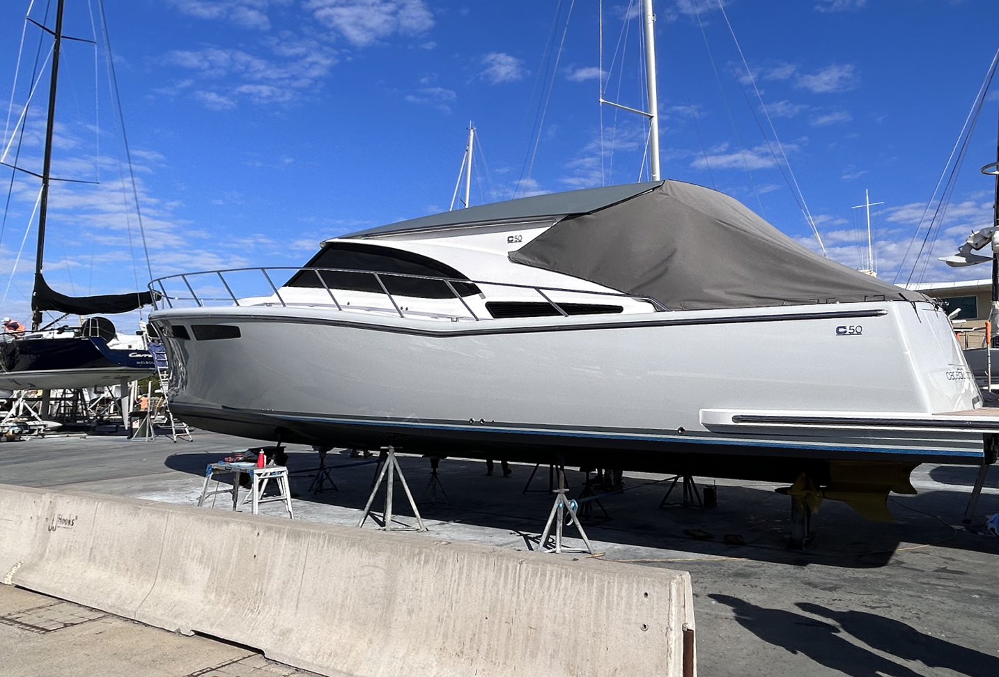 Luxury motor yacht preparation: Grey vessel on boat stands prior to full shrink wrap encapsulation for refit.
